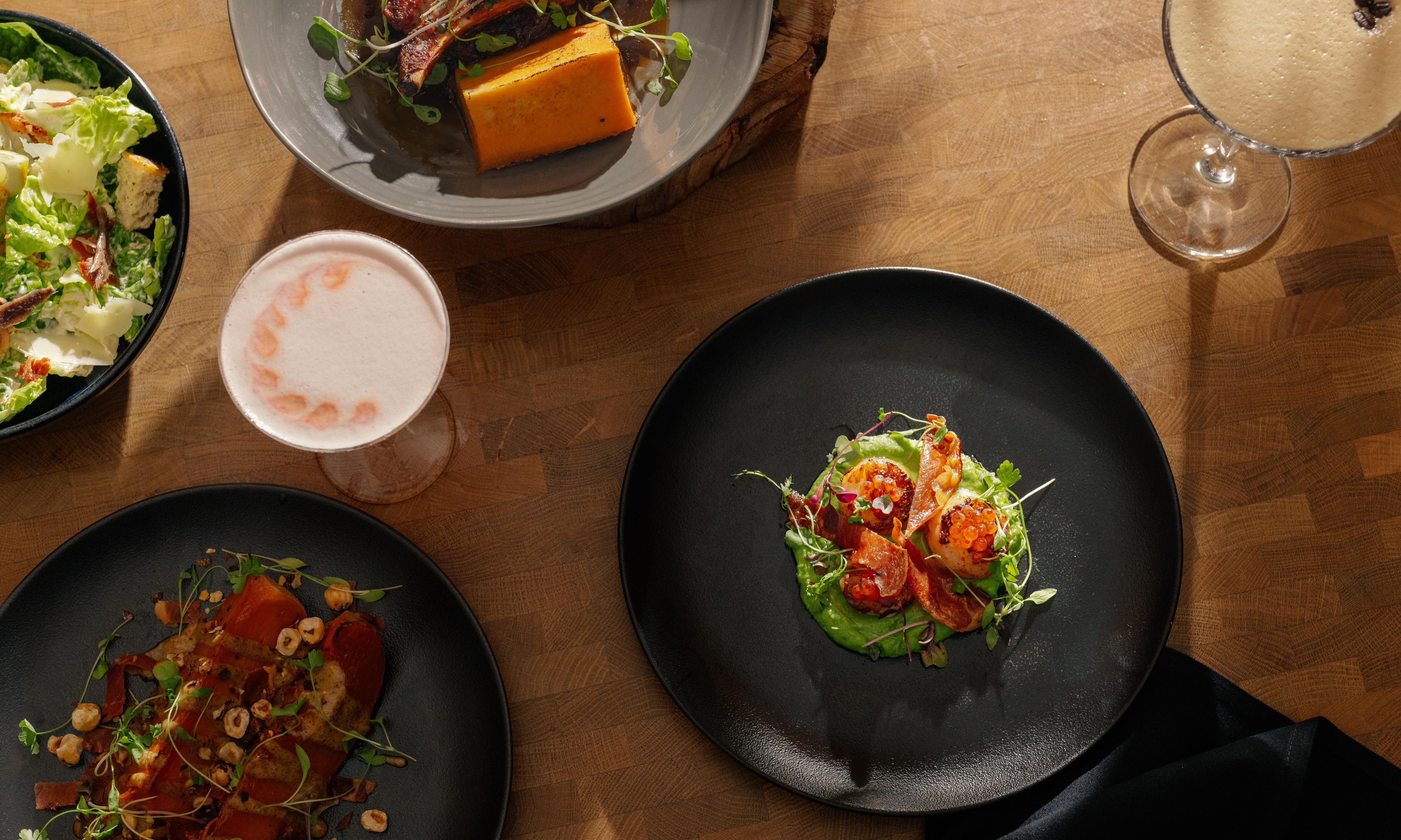 Meals on dark plates upon a wooden table